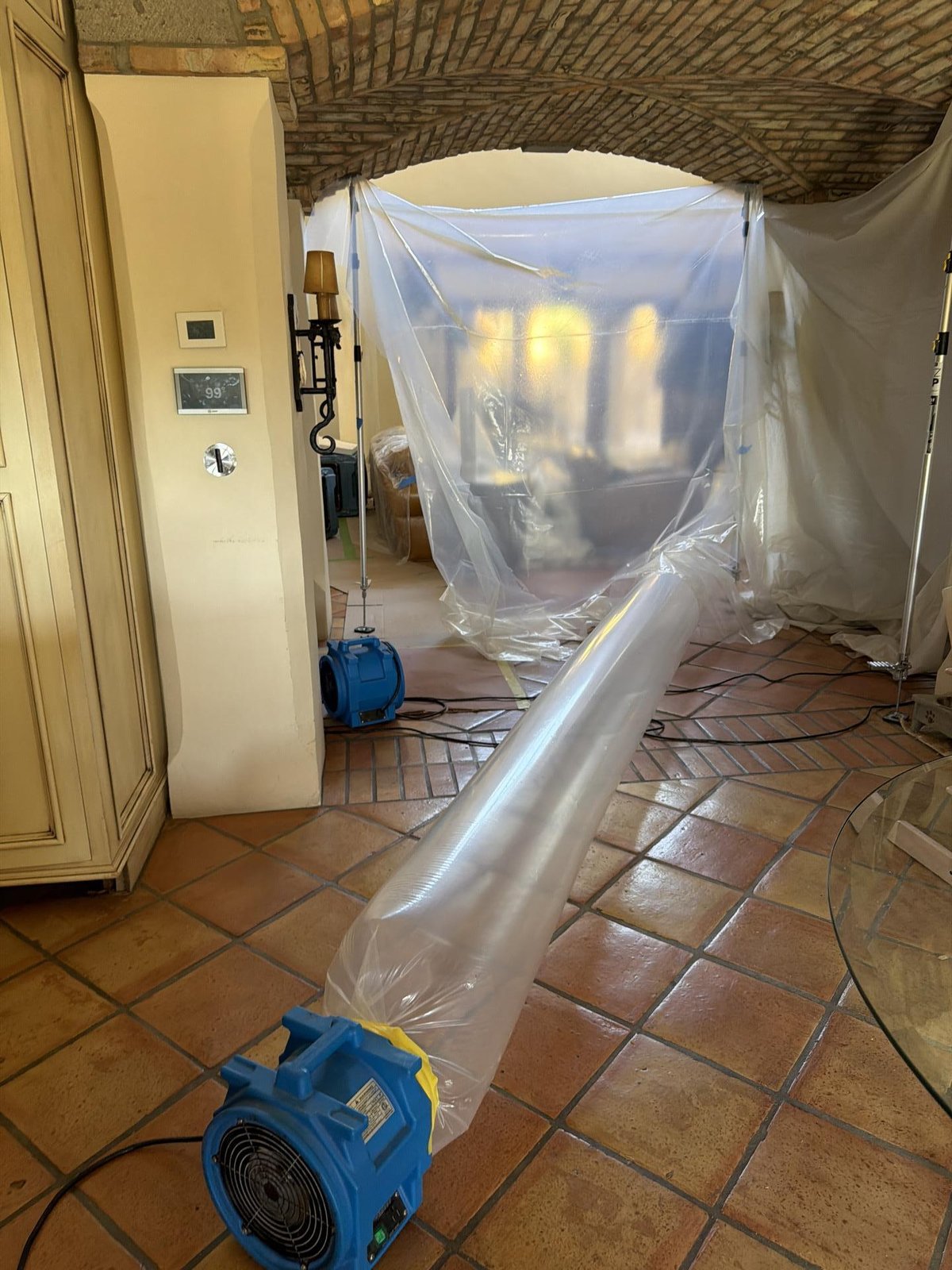 Sealed poly containment chamber with lay-flat ducting venting warm air across a Saltillo tile floor during structural drying of a Paradise Valley masonry home